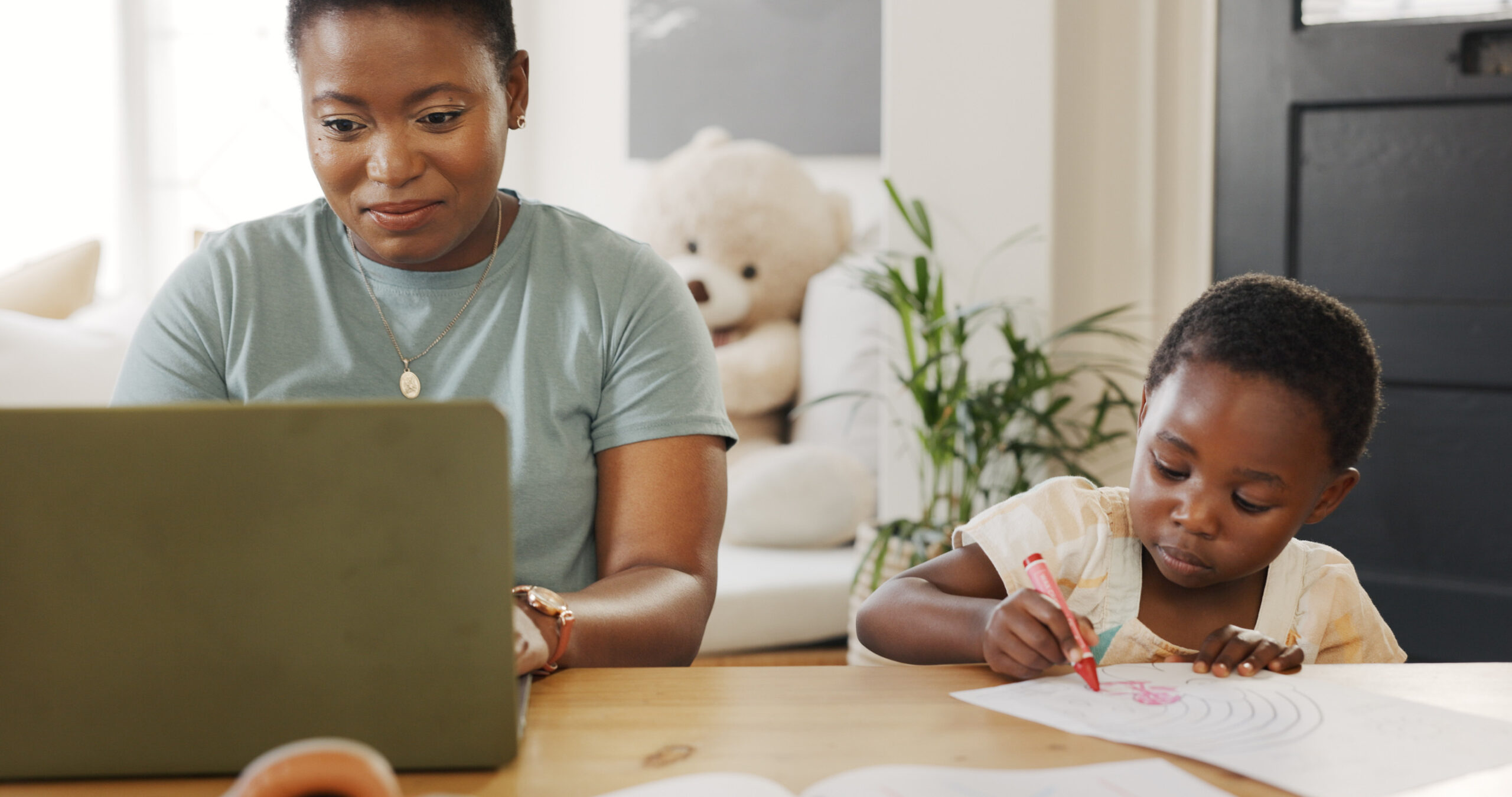 parent working on laptop while child draws
